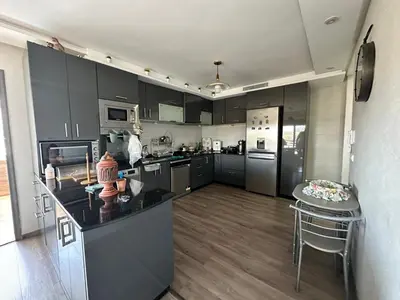 a large kitchen with black cabinets and a counter top at Les jardins de cherrat in Bouznika
