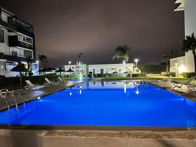 a large blue swimming pool in front of a building at Les jardins de cherrat in Bouznika