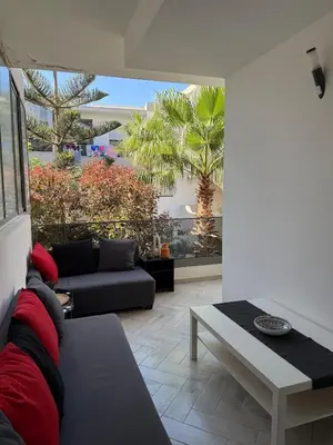a living room with a couch and a table at Appartement Moderne 2 chambres à Blanca Beach Sidi Rahal in Sidi Rahal