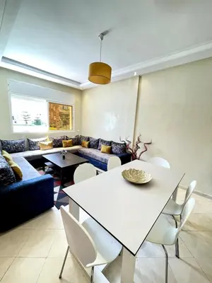 a living room with a table and a couch at Appartement à Sidi Rahal Piscine et Accès direct plage in Sidi Rahal