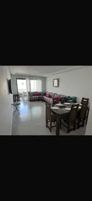 a living room with a table and chairs and a couch at Blue dhalia beach a sidi rahal in Dar Oulad Hajj Kassem