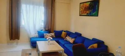 a living room with a blue couch and a table at Appartement Alhadika in Casablanca