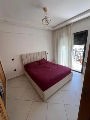 a bedroom with a bed with a red comforter and a window at Dar laakbira in Bouznika