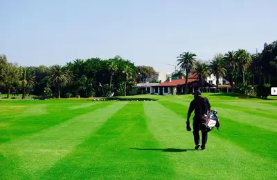 a man walking across a green field with a backpack at 2 rooms in Park near Beach and Golf in Mohammedia