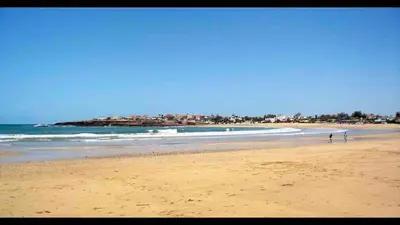 a beach with people walking on the sand and the ocean at 2 rooms in Park near Beach and Golf in Mohammedia
