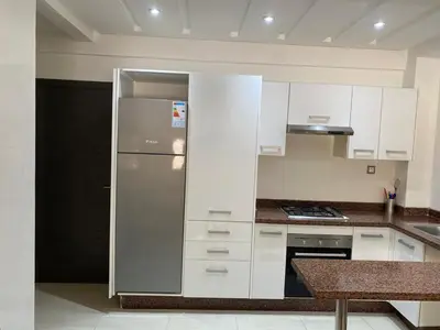 a kitchen with white cabinets and a stainless steel refrigerator at Cozy Relax in Mohammedia