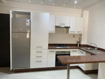 a kitchen with white cabinets and a stainless steel refrigerator at Cozy Relax in Mohammedia