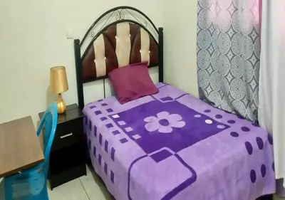 a purple bed with a purple comforter and a table at Appartement Spacieux pour Famille Mâarif Casablanca in Maarif