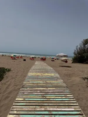 a boardwalk on a beach with chairs and umbrellas at Modern appartment in Casablanca