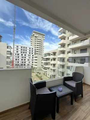 a balcony with chairs and a table with a view of a building at Cozy Studio Vue sur Piscine à Ocean Park Zenata City Eco in Aïn Harrouda