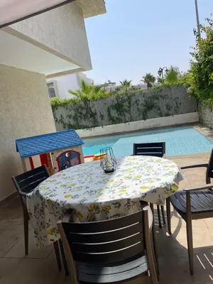 a table and chairs with a table and a pool at Villa a darbouaza in Dar Bouazza