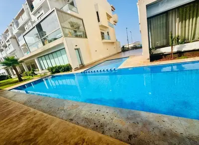 a large blue swimming pool in front of a building at Appartement Mer & Soleil à EL Mansoria in Pont Blondin