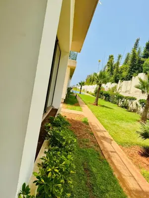 a porch of a house with a green yard at Appartement Mer & Soleil à EL Mansoria in Pont Blondin