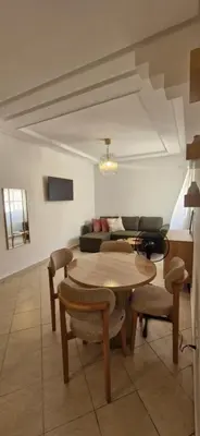 a living room with a table and a couch at Séjour Idéal Piscine & Sécurité in Bouznika