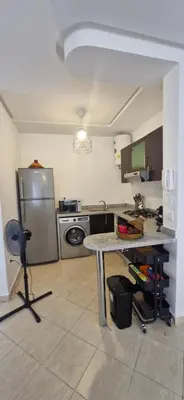 a kitchen with a table and a stainless steel refrigerator at Séjour Idéal Piscine & Sécurité in Bouznika