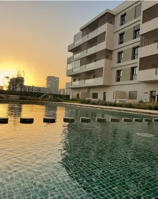 a swimming pool in front of a building at Appartement Neuf & Cosy avec vu sur mer -Zenata Eco City- in Aïn Harrouda