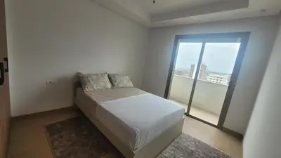 a small bedroom with a bed and a large window at Appartement Neuf & Cosy avec vu sur mer -Zenata Eco City- in Aïn Harrouda