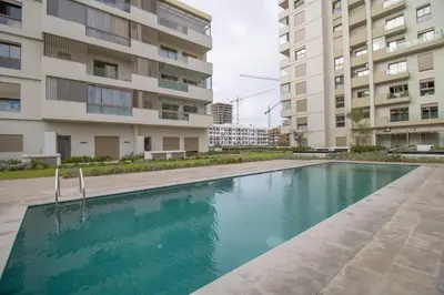 a swimming pool in front of two buildings at Appartement Neuf & Cosy avec vu sur mer -Zenata Eco City- in Aïn Harrouda