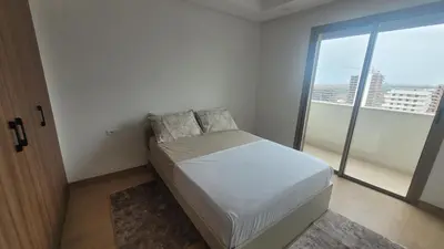 a small bedroom with a bed and a large window at Appartement Neuf & Cosy avec vu sur mer -Zenata Eco City- in Aïn Harrouda