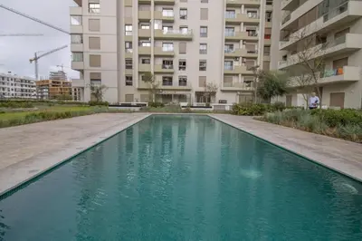 a pool of blue water in front of a building at Appartement Neuf & Cosy avec vu sur mer -Zenata Eco City- in Aïn Harrouda