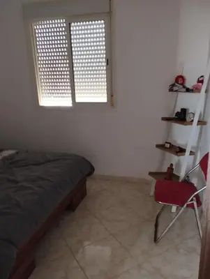 a bedroom with a bed and a red chair at Khalid in Bouznika