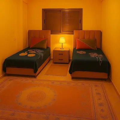 two beds in a room with a night stand and a lamp at Résidence calme 3 chambres pour votre hébergement in Bouznika