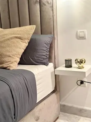 a bed with a wooden headboard and a side table at Studio chic Palmier in Casablanca