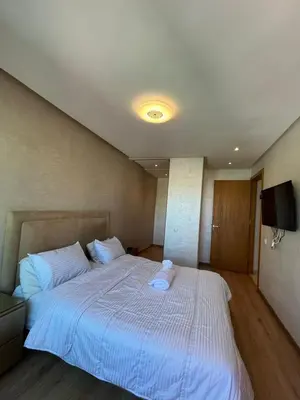 a large white bed in a room with a television at cozy furnished studio fully equipped in Casablanca
