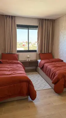 a bedroom with two beds and a window at Flat in Sidi Rahal Chatai with Ocean View in Sidi Rahal
