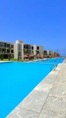 a large blue swimming pool with buildings in the background at Appartement Haut Standing vue Piscine in Sidi Rahal