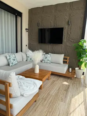 a living room with a couch and a tv on a wall at Appartement Haut Standing vue Piscine in Sidi Rahal