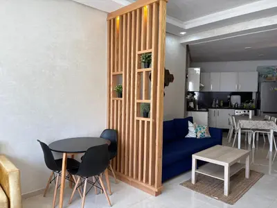 a living room with a blue couch and a table at Appartement Residence Mansbay - Piscine - Accès Plage - WIFI in Mohammedia