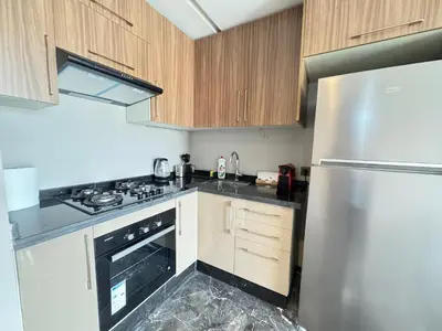 a kitchen with wooden cabinets and a stainless steel refrigerator at Élégant Studio Neuf Quartier 2 Mars Sécurisé in Aïn Chock