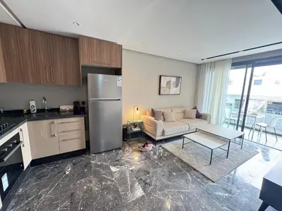 a kitchen and living room with a couch and a table at Élégant Studio Neuf Quartier 2 Mars Sécurisé in Aïn Chock