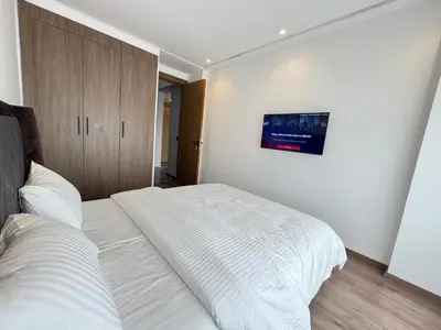 a bedroom with a large white bed and a cabinet at Élégant Studio Neuf Quartier 2 Mars Sécurisé in Aïn Chock