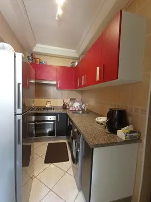 a kitchen with red cabinets and a refrigerator at SUMMER AND FAMILY APPARTEMMENT ,mouhamadia in Mohammedia
