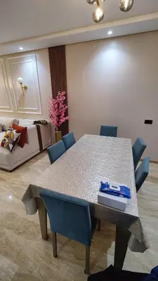 a dining room with a table and chairs and a couch at Appartement de prestige à Dar bouazza avec plusieurs piscines et à proximité à la plage in Tamaris