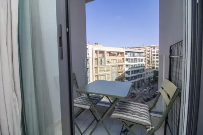 a table and chairs on a balcony with a view of a city at Studio Confortable et Cozy 5 min du stade CAN2025- Maarif Casablanca in Casablanca
