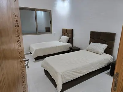 a room with two beds and a window at Appart Bouznika neuf in Bouznika