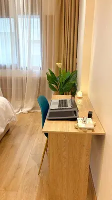 a laptop on a wooden desk with a potted plant at Cosy studio Steps to Shore and Tramway in Rabat