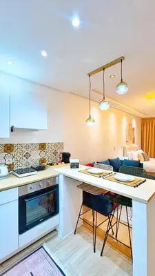 a kitchen with a counter top and a living room at Cosy studio Steps to Shore and Tramway in Rabat
