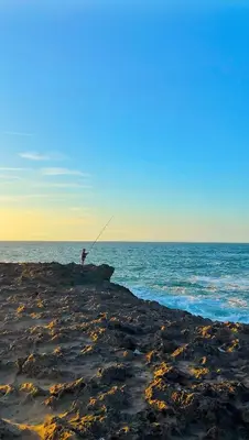 a person is fishing on a rock in the ocean at Cosy studio Steps to Shore and Tramway in Rabat