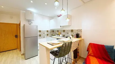 a small kitchen with a counter and a refrigerator at Cosy studio Steps to Shore and Tramway in Rabat