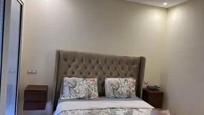 a bed with a padded headboard and two pillows at Luxe appartement in Bouznika