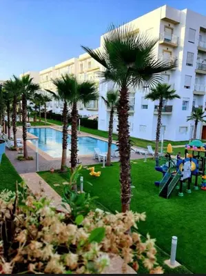 a resort with palm trees and a swimming pool at Luxe appartement in Bouznika