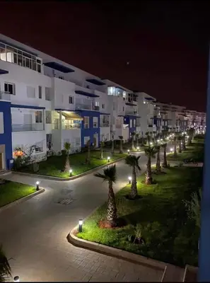 a row of palm trees in front of a building at night at Appartement lux a mansoria les terrasses 2 et 3 in Mansouria