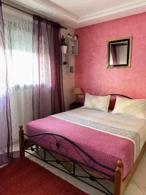 a pink bedroom with a bed and a window at Residence sables dor Mohammedia in Mohammedia