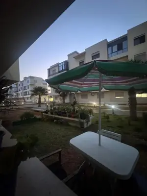 a table with an umbrella in front of a building at Residence sables dor Mohammedia in Mohammedia