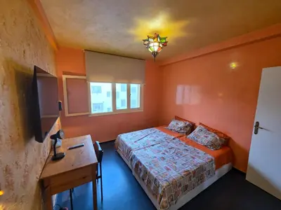 a bedroom with orange walls and a bed and a desk at SUNSET Room in Rabat