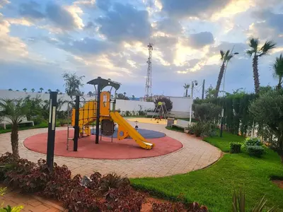 a playground with a yellow slide in a park at Bouznika Apartement de luxe 2 Chambres RDC in Bouznika
